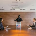 Three professionals deliberating in a modern conference room setting.